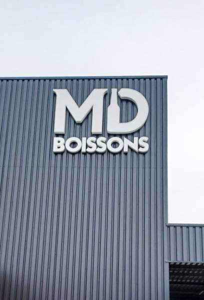 Installation d’une enseigne extérieure MD BOISSONS en lettres individuelles sur façade métallique à Rouffach (68).
