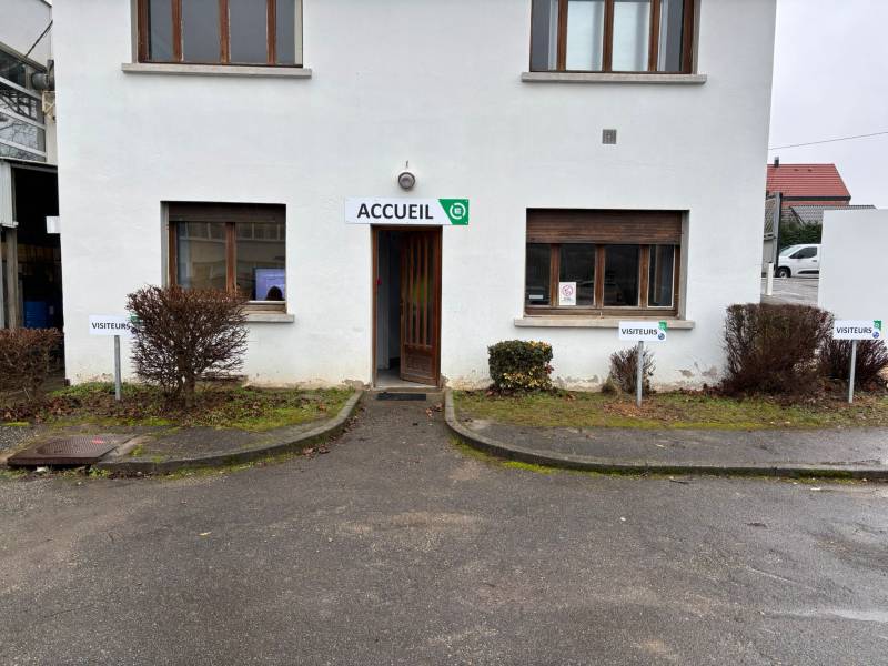 Enseigne d’accueil en panneau Dibond fixée en façade, offrant une signalétique visible, lisible et cohérente avec l’identité graphique du site.